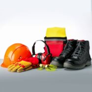 Conjunto de equipamentos de proteção individual com capacete laranja, luvas de proteção amarelas e vermelhas, protetor auricular tipo concha, óculos de segurança amarelos, botas de segurança pretas e bolsa de ferramentas vermelha e amarela.